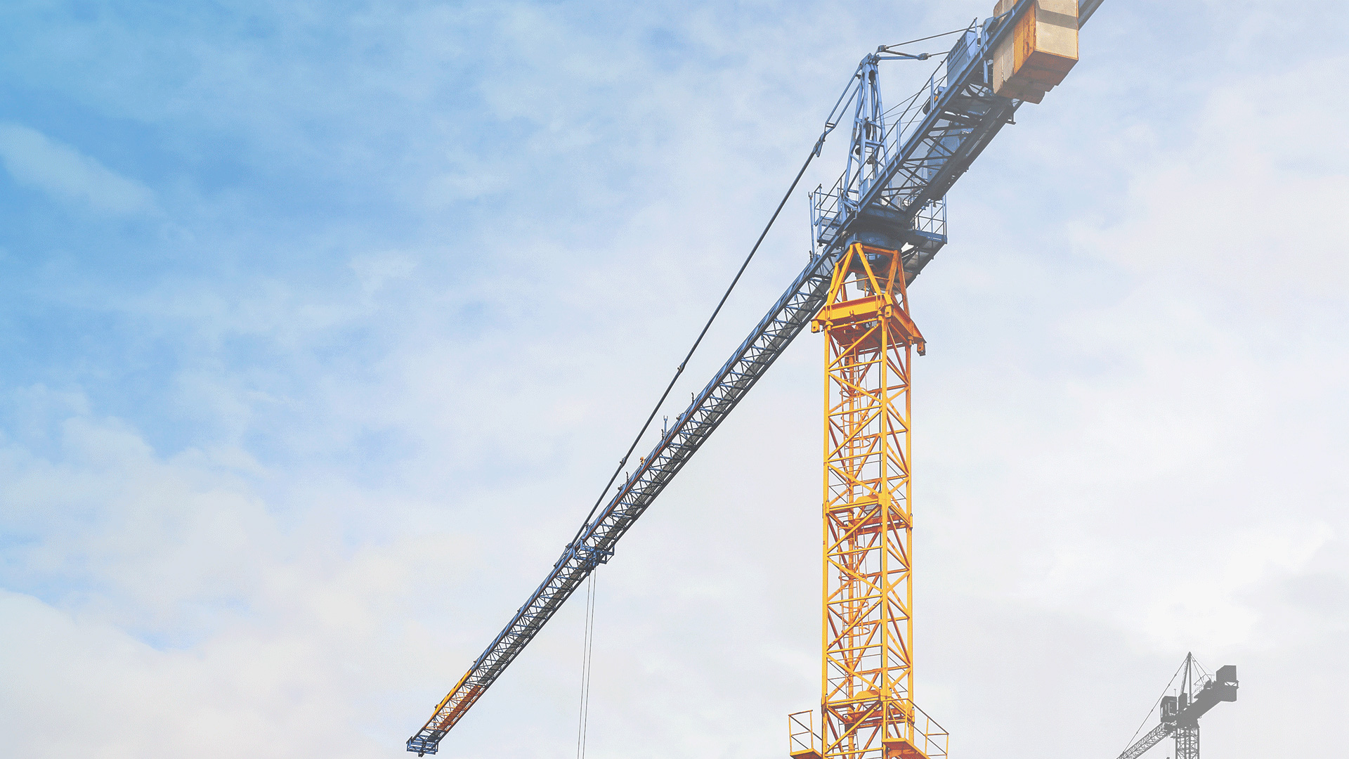 Yellow construction crane in front of clear skies